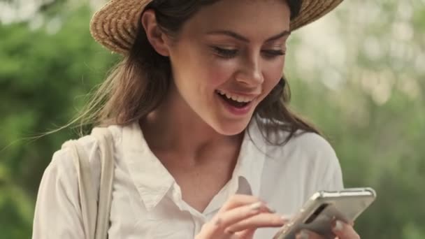 Mujer Atractiva Agradable Usando Sombrero Usando Teléfono Inteligente Mientras Está — Vídeos de Stock