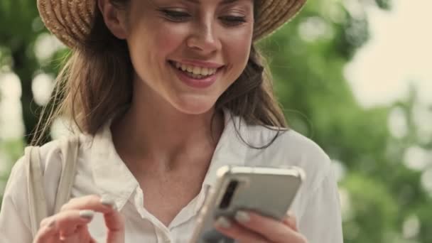 Vrolijke Aantrekkelijke Vrouw Met Hoed Schrijven Bericht Smartphone Tijdens Het — Stockvideo