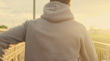 Kulaklıklı genç bir sporcunun arka görüntüsü sabah köprüde koşuyor.