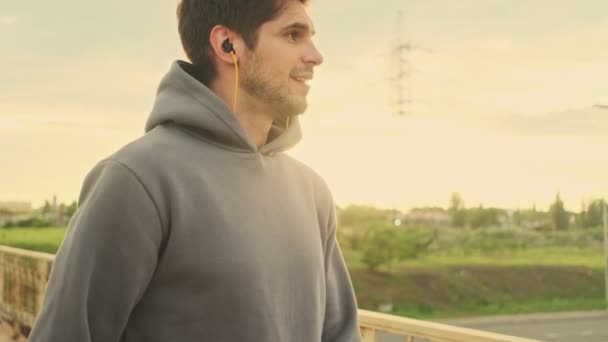 Een Lachende Jonge Sporter Met Oortjes Loopt Morgens Buiten Brug — Stockvideo