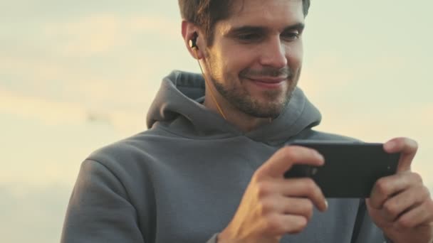 Ein Gutaussehender Junger Sportler Beobachtet Etwas Auf Seinem Smartphone Während — Stockvideo