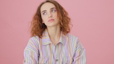 Üzgün genç bir kadın ağlıyor. Stüdyoda pembe bir arka planda tek başına duruyor.