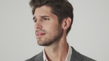 Yakışıklı genç iş adamı beyaz duvarın üzerinden izole edilmiş bir şekilde etrafa bakıyor.