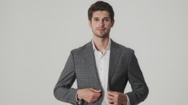 Genç iş adamı gömleğini ve ceketini iliklerken beyaz duvarın üzerinden izole edilmiş.