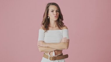 Kendine güveni tam genç bir kadın stüdyoda pembe arka planda duran bir şeyi reddediyor.