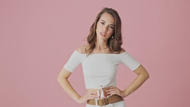 一位不高兴的年轻女子在演播室里 站在粉红的背景上 露出垂头丧气的姿态 — 图库视频影像