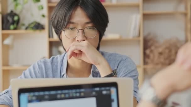Konsentrat Pemuda Asia Menggunakan Laptop Sambil Duduk Meja Dengan Rekannya — Stok Video