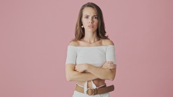 一位严肃的年轻女子正在演播室里做着沉默的姿势 孤零零地站在粉红的背景下 — 图库视频影像