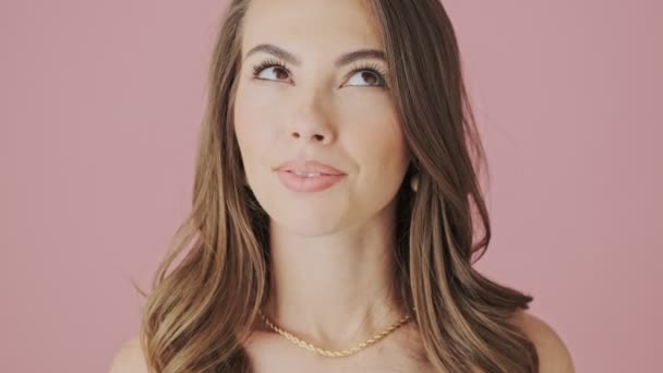 Крупный План Улыбающейся Молодой Женщины Мечтает Стоящем Изолированном Розовом Фоне — стоковое видео