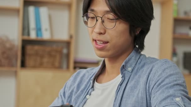 Ofiste Masa Başında Oturan Asyalı Genç Adam Arkadaşıyla Bir Şeyler — Stok video