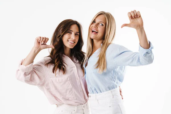 Imagen Dos Hermosas Mujeres Sonrientes Apuntándose Con Los Dedos Mientras —  Fotos de Stock