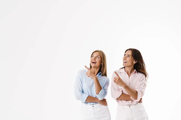 Imagem Excitado Caucasiano Duas Mulheres Apontando Dedos Lado Sorrindo Isolado — Fotografia de Stock