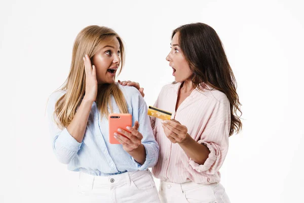 Изображение Удивленных Веселых Двух Женщин Использующих Мобильный Телефон Держащих Кредитную — стоковое фото