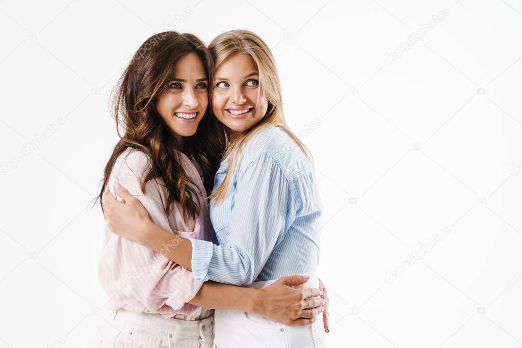 Image of happy beautiful two women smiling and hugging isolated over white background