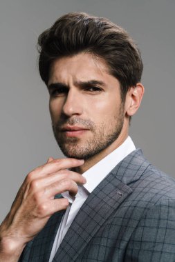 Ceketli saygıdeğer iş adamının fotoğrafı. Gri duvardan izole edilmiş kameraya bakıyor ve poz veriyor.