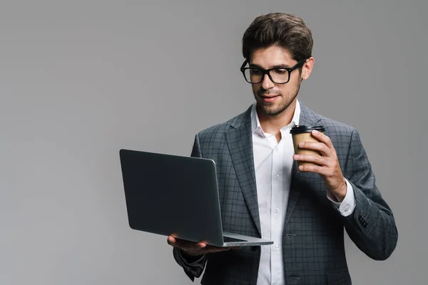 Foto Empresário Focado Óculos Bebendo Café Usando Laptop Isolado Sobre — Fotografia de Stock