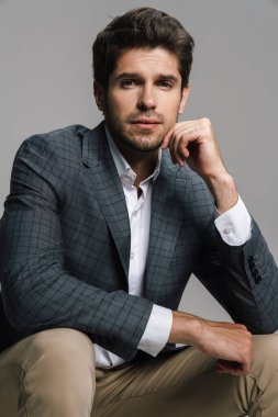 Ceketli saygıdeğer iş adamının fotoğrafı gri duvarın üzerinde izole bir şekilde oturuyor ve kameraya bakıyor.