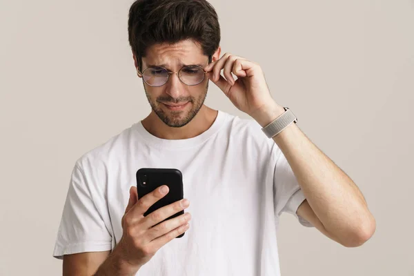 Porträtt Missnöjd Stilig Man Glasögon Med Mobiltelefon Isolerad Över Vit — Stockfoto