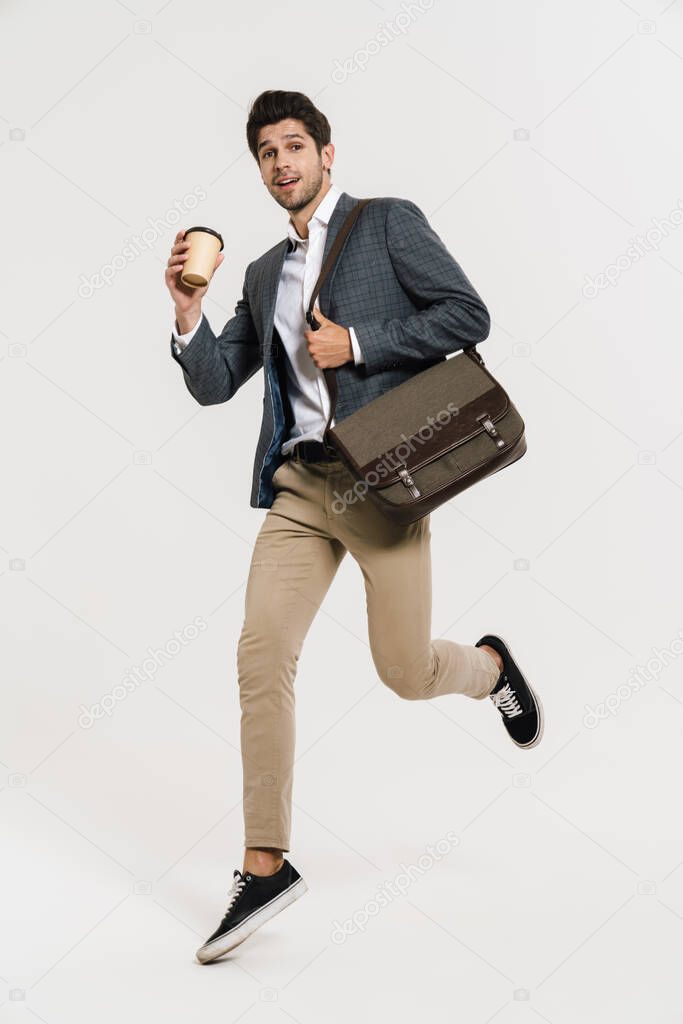Photo of pleased caucasian businessman drinking coffee while running with bag isolated over white wall