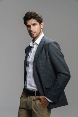 Ceketli saygıdeğer iş adamının fotoğrafı. Gri duvardan izole edilmiş kameraya bakıyor ve poz veriyor.