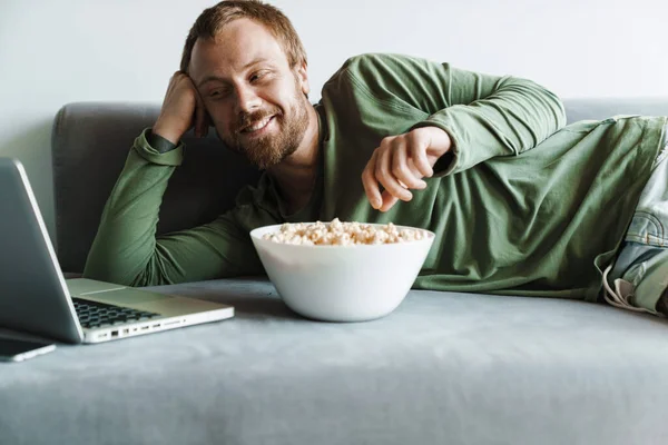 Photo Young Cheerful Man Beard Watching Movie Laptop While Eating — Stock Photo, Image