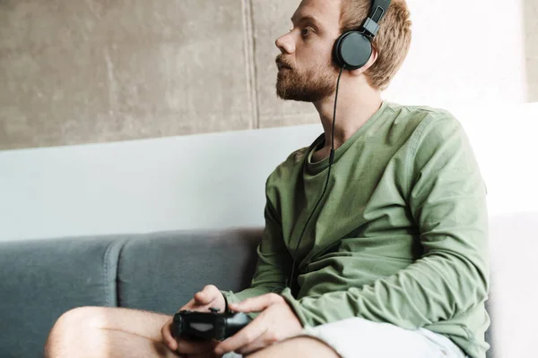 Foto Hombre Enfocado Usando Auriculares Jugando Videojuegos Con Joystick Mientras —  Fotos de Stock