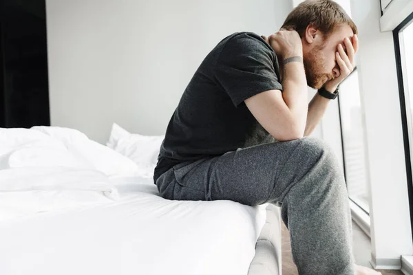 Foto Homem Ruivo Descontente Cobrindo Seu Rosto Enquanto Sentado Cama — Fotografia de Stock