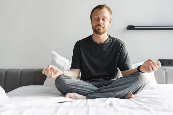 Photo Pleased Redhead Man Meditating Eyes Closed While Sitting Bed — Stock Photo, Image
