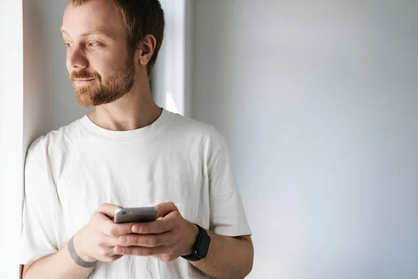 Photo Pleased Bearded Man Red Hair Using Mobile Phone While — Stock Photo, Image
