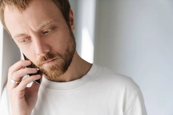 Foto Hombre Barbudo Perplejo Hablando Teléfono Móvil Mientras Apoya Pared — Foto de Stock