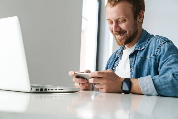 Fénykép Mosolygós Jóképű Férfi Játszik Online Játék Mobiltelefon Miközben Dolgozik — Stock Fotó