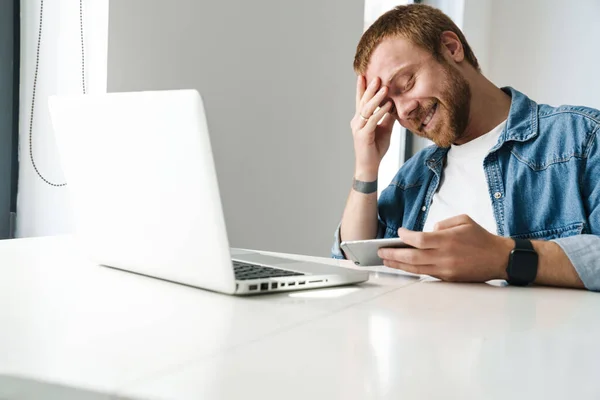 Foto Homem Bonito Sorrindo Jogando Jogo Online Celular Enquanto Trabalhava — Fotografia de Stock