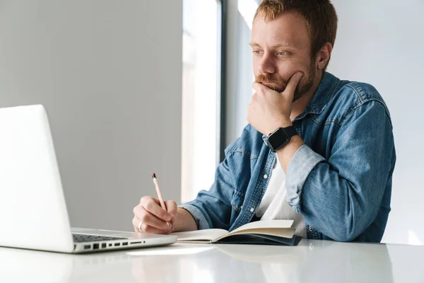 Foto Hombre Guapo Pensando Escribir Notas Mientras Trabaja Con Ordenador — Foto de Stock