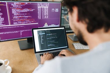 Ofisteki bilgisayarlarla çalışan gözlüklü beyaz programcı görüntüsü