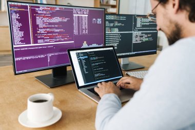 Ofisteki bilgisayarlarla çalışırken klavyede yazan programcının kırpılmış resmi