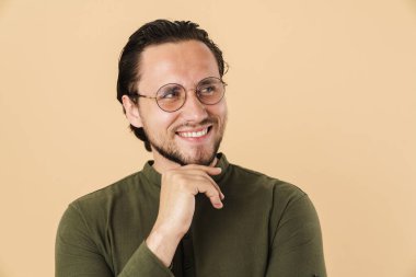 Gözlük takan, gülümseyen ve bej arka planda soyutlanmış genç bir adamın görüntüsü.