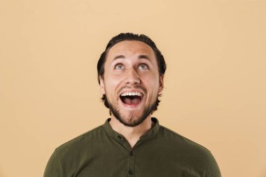 Mutlu sakallı bir adamın bej arka planda izole bir şekilde yukarı bakıp gülerken görüntüsü