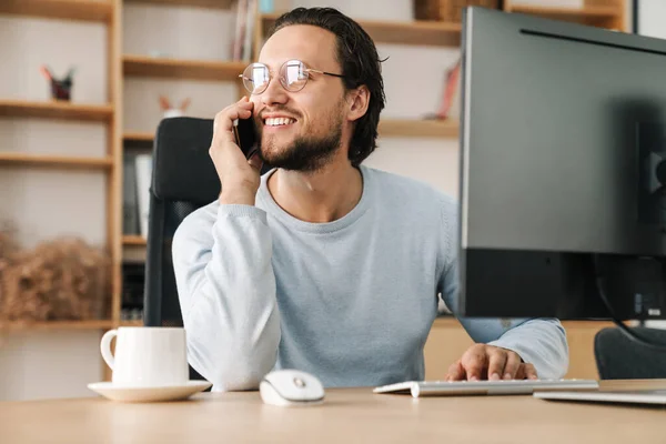 Imagem Homem Programador Sorrindo Usando Óculos Falando Celular Enquanto Trabalhava — Fotografia de Stock