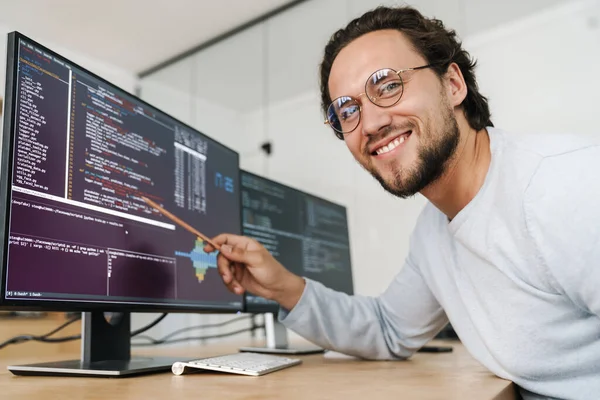 Obraz Uśmiechniętego Nieogolonego Programisty Noszącego Okulary Pracującego Komputerami Biurze — Zdjęcie stockowe