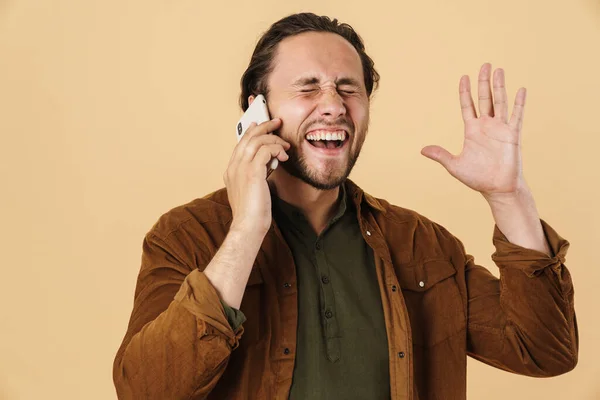 Obraz Podekscytowanego Młodzieńca Rozmawiającego Przez Telefon Komórkowy Krzyczącego Odizolowanego Beżowym — Zdjęcie stockowe