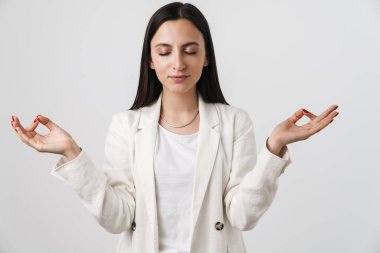 Genç sakin iş kadınının meditasyon yaptığı ve parmaklarını bir arada tuttuğu fotoğraf beyaz arka planda izole edilmiş.