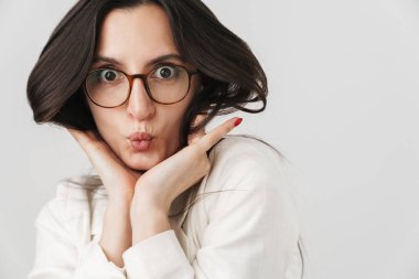 Eğlenceli iş kadınının beyaz arka planda izole edilmiş kamera önünde dalga geçtiği ve yüzünü buruşturduğu fotoğraf