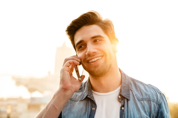 Photo Joyful Handsome Man Smiling Talking Mobile Phone While Walking — Stock Photo, Image