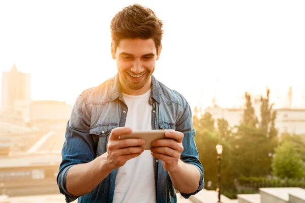 Photo Excited Handsome Man Smiling Playing Online Game Mobile Phone — Stock Photo, Image