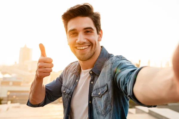 Foto Gioioso Unshaven Giovane Uomo Mostrando Pollice Mentre Prende Selfie — Foto Stock