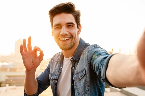 Foto Joven Alegre Sin Afeitar Haciendo Gestos Signo Mientras Toma — Foto de Stock