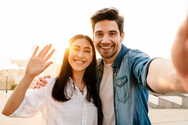 Imagen Una Sonriente Pareja Multicultural Saludando Con Mano Tomando Fotos — Foto de Stock