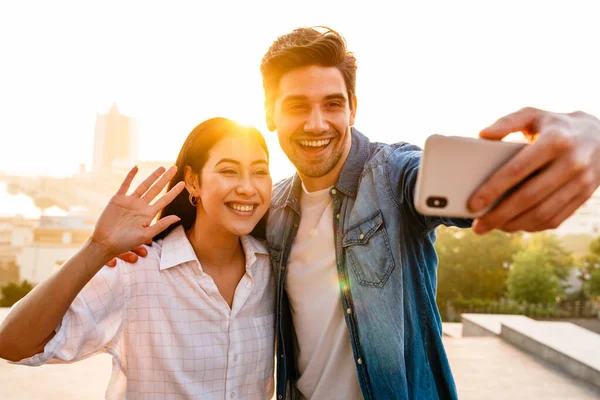 Imagem Casal Multicultural Feliz Acenando Mão Tirando Foto Selfie Celular — Fotografia de Stock