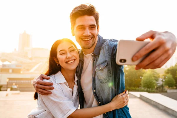 Imagen Una Pareja Multicultural Sonriente Abrazando Tomando Fotos Selfies Teléfono — Foto de Stock