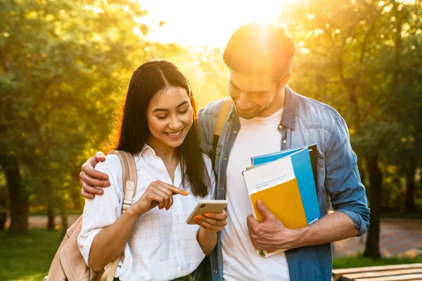 Obraz Wesołej Wielokulturowej Pary Studenckiej Korzystającej Telefonu Komórkowego Uśmiechającej Się — Zdjęcie stockowe